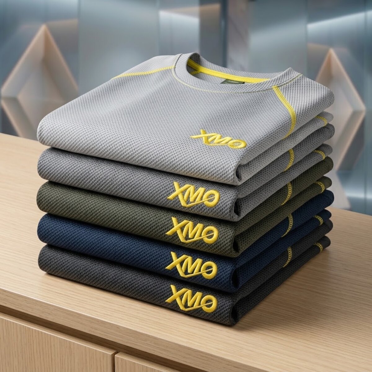 Gestapelte XMO Cool-Touch-Shirts in fünf Farben mit gelber Naht